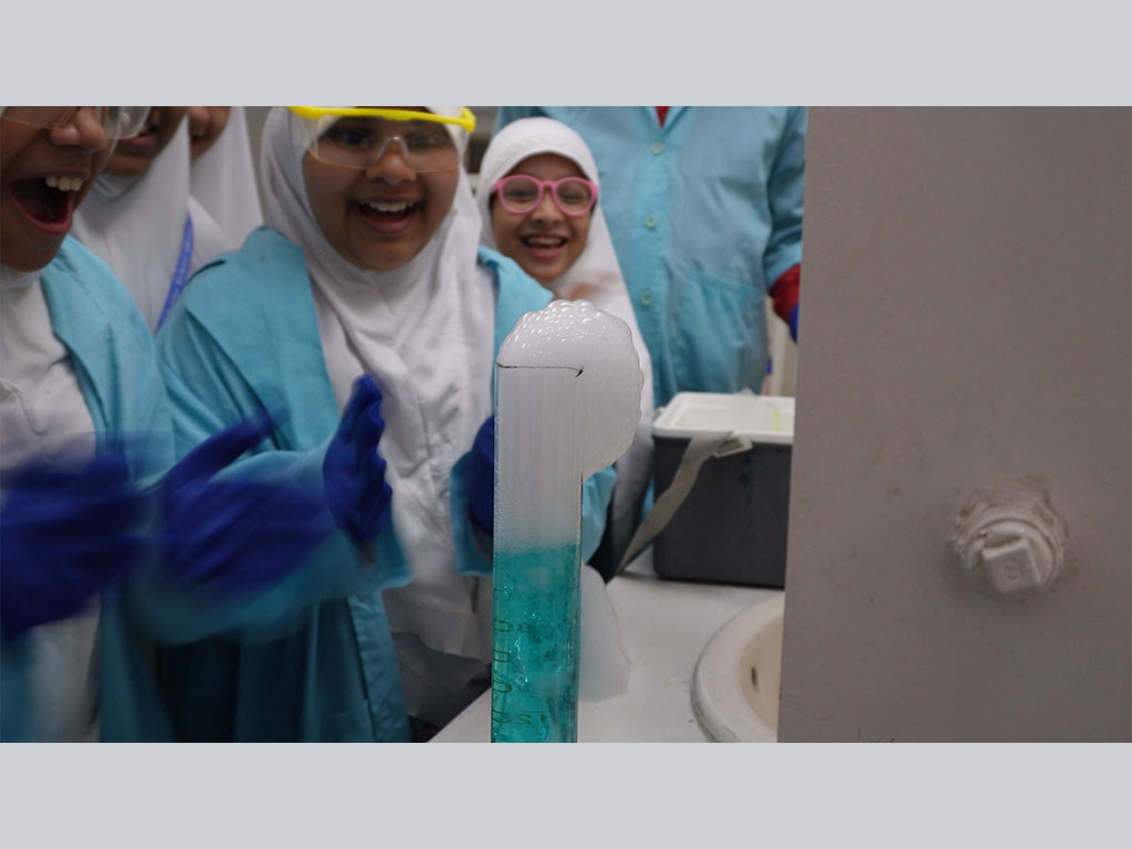 Students watching, forming snake bubbles with solid carbon dioxide in laboratory classroom